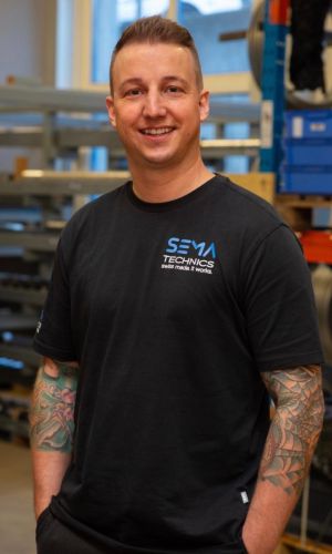 Severin Häuselmann mit Sema Technics AG Shirt porträtiert vor Gestell mit Pressringen.
