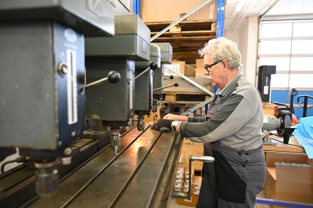 Mann stanzt Löcher in eine V2A Metallscheibe für einen Pressring.