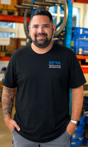 Rolf Keller mit Sema Technics AG Shirt porträtiert vor Gestell mit Pressringen.