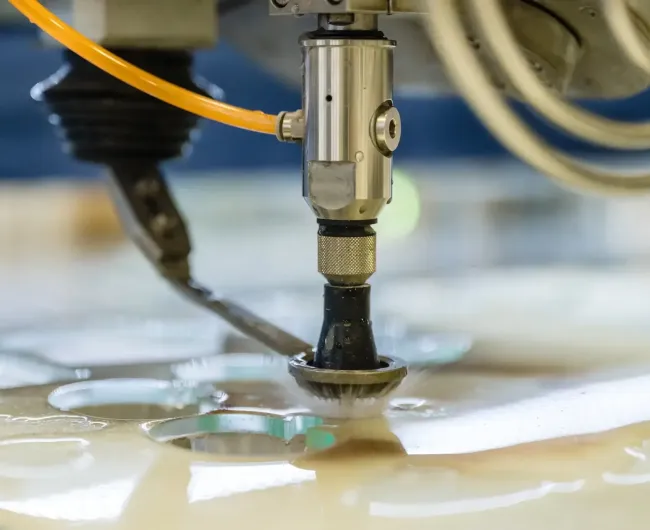 Wasserstrahlkopf der etwas aus einer Metallplatte ausschneidet.